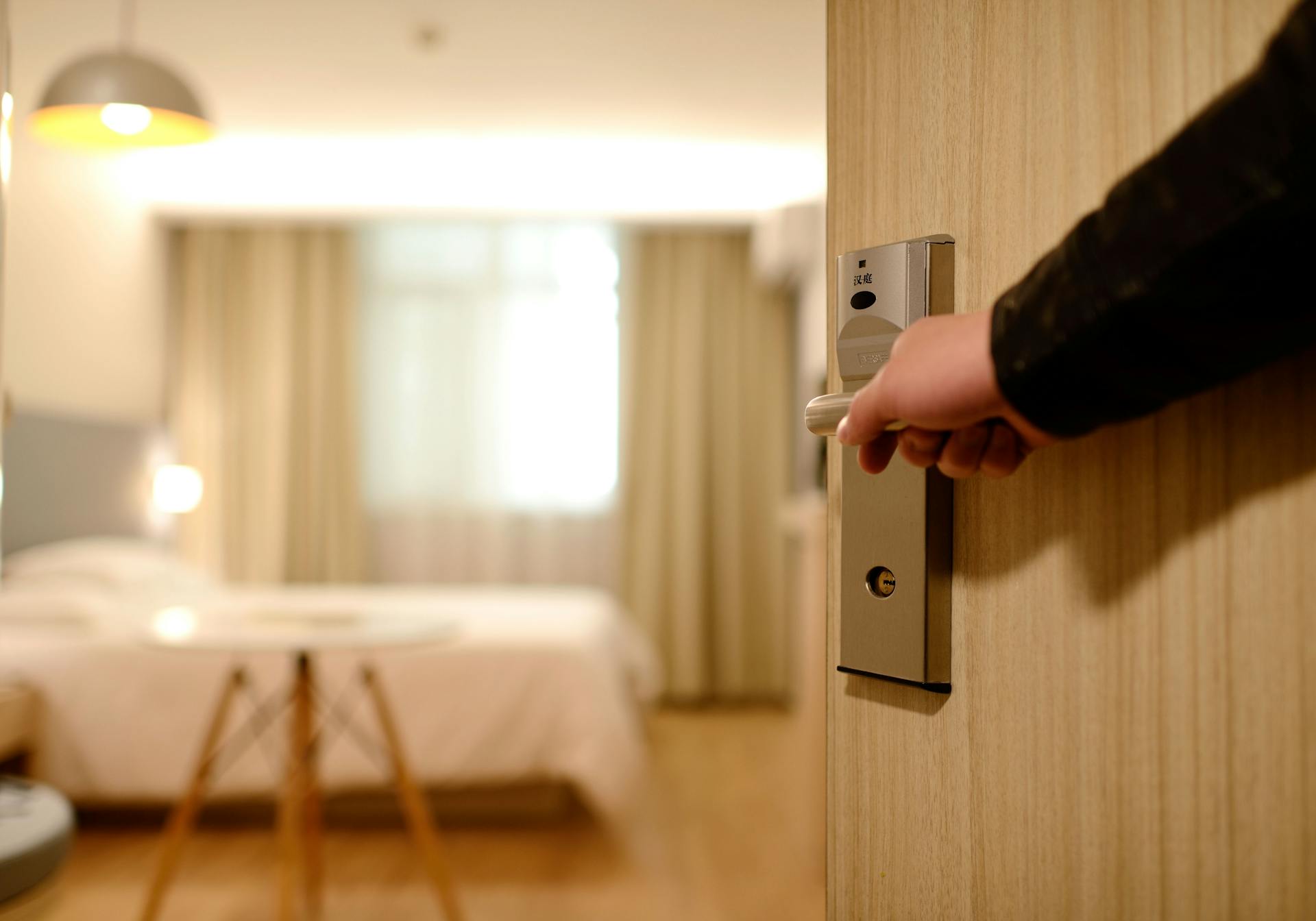 A hotel room being opened with the door and lock visible.
